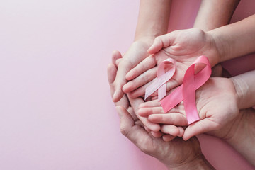 hands holding pink ribbons on pink background, Breast cancer awareness and October Pink day, World cancer day