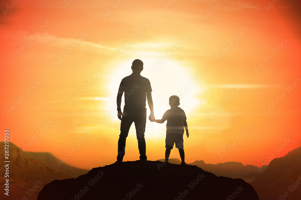 Father and son holding hand in hand at the sunset time.