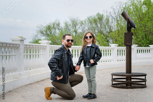 Fashionable stylish family portrait for a walk. Dad and daughter posing on the observation deck. Excursion. Travel and tourism concept. Time together. Family look. Urban casual outfit.  photo