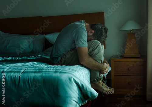 Fotografie dramatic lifestyle portrait of man sitting depressed on bed crying desperate fee