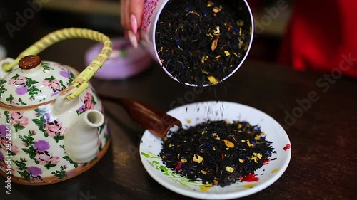 Person spoons loose-leaf tea out of the metal can into the plate