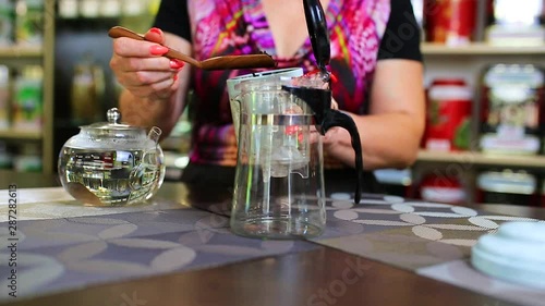 Person spoons loose-leaf tea into the glass carafe, fills it with hot water and brews up tea