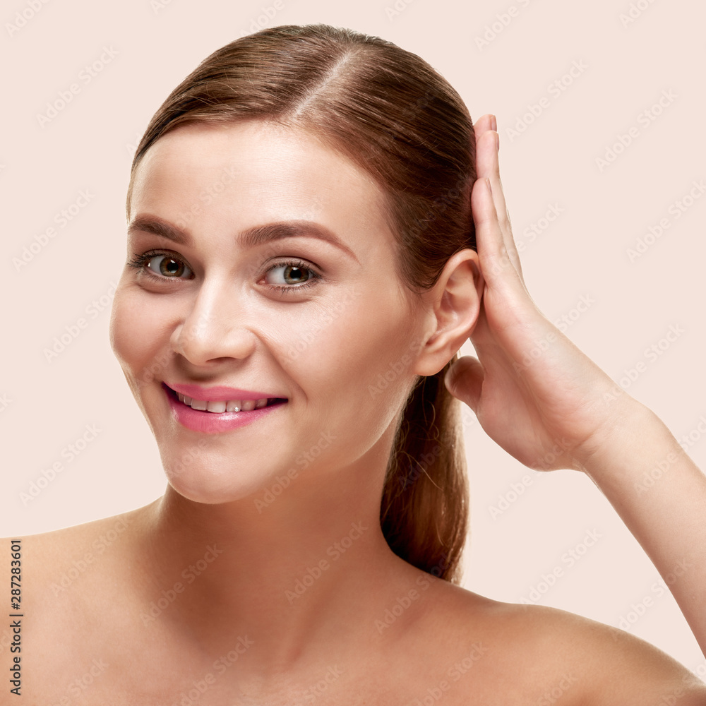 Attractive smiling woman touching her healthy shiny hair, on light color background