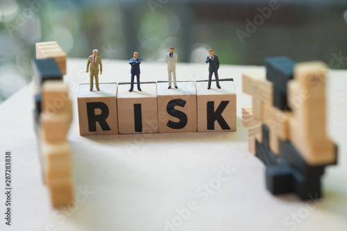 Miniature people businessmen stand on cube word with risk. Risk analysis for investment