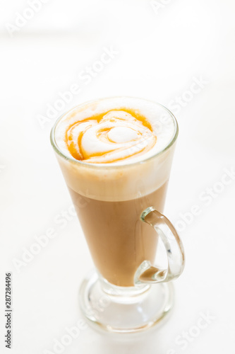 Hot caramel macchiato in a tall glass with caramel sauce on top close up.