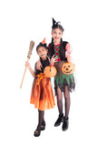 Full length of two asian girls in witch costume holding halloween pumpkin bucket and smile over white background