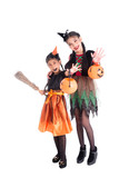 Full length of two asian girls in witch costume holding halloween pumpkin bucket and smile over white background
