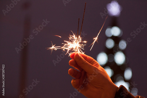 Bengal fire in man hands on Christmas tree lights background