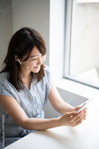 Young woman talking on smart phone with wireless head set