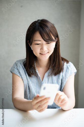Young woman talking on smart phone with wireless head set