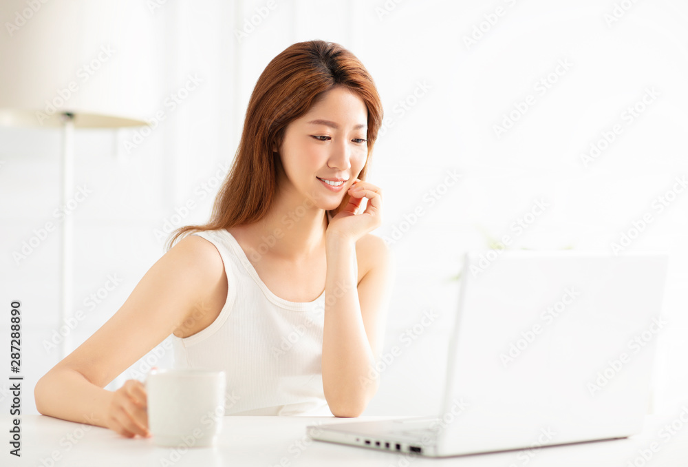 smiling young woman using laptop in living room smiling young woman using laptop in living room