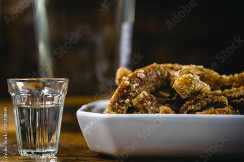 Cachaça, drops, cane or sugar cane is the name given to brandy produced in Brazil. Served with pork crackling. Typical food and drinks from Brazilian restaurants or bars. photo