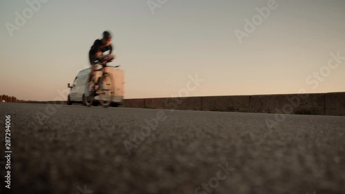 Cyclist Cycling Triathlete On Road Bicycle In Sunset.Cyclist In Helmet Riding On Sunset Time.Portrait Fit Bicyclis In Sunglasses Intensive Training Cycling Before Triathlon Competition.Hard Training. photo