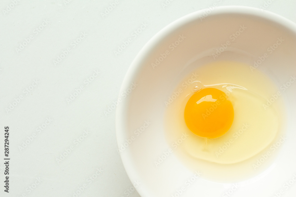 Fresh raw egg in bowl on white background. Fresh raw egg in bowl on white background.