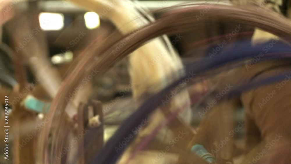 A closeup shot and racking focus on a couple of wooden spinning wheels in motion, used in the traditional silk-making production. A closeup shot and racking focus on a couple of wooden spinning wheels in motion, used in the traditional silk-making production.