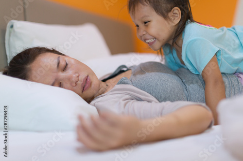 Sleepy mother trying to rest with her child in bed.