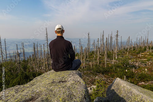 Young man tourist sittiing on top of mountain, Sumava National Park and Bavarian Forest, Czech republic and Germany photo