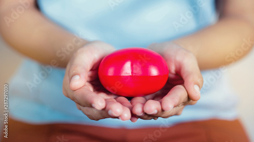 Fényképezés Closeup of a girl hand holding a red heart