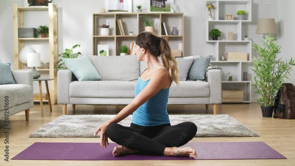 Pretty woman in sportswear sitting on floor at home and stretching Pretty woman in sportswear sitting on floor at home and stretching