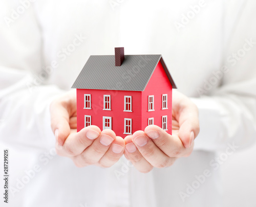 Small red toy house in hands 