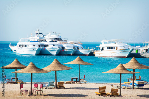 Beach with umbrellas. On the sea yachts.