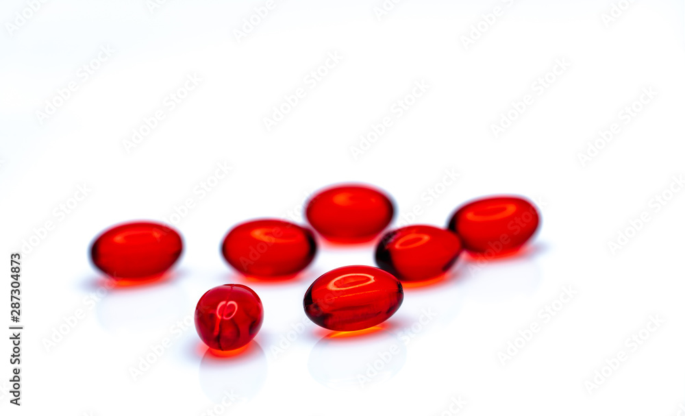 Red soft gel capsule pills isolated on white background. Pile of red soft gelatin capsule. Vitamins and dietary supplements concept. Pharmaceutical industry. Pharmacy drug store. Health care products. Red soft gel capsule pills isolated on white background. Pile of red soft gelatin capsule. Vitamins and dietary supplements concept. Pharmaceutical industry. Pharmacy drug store. Health care products.