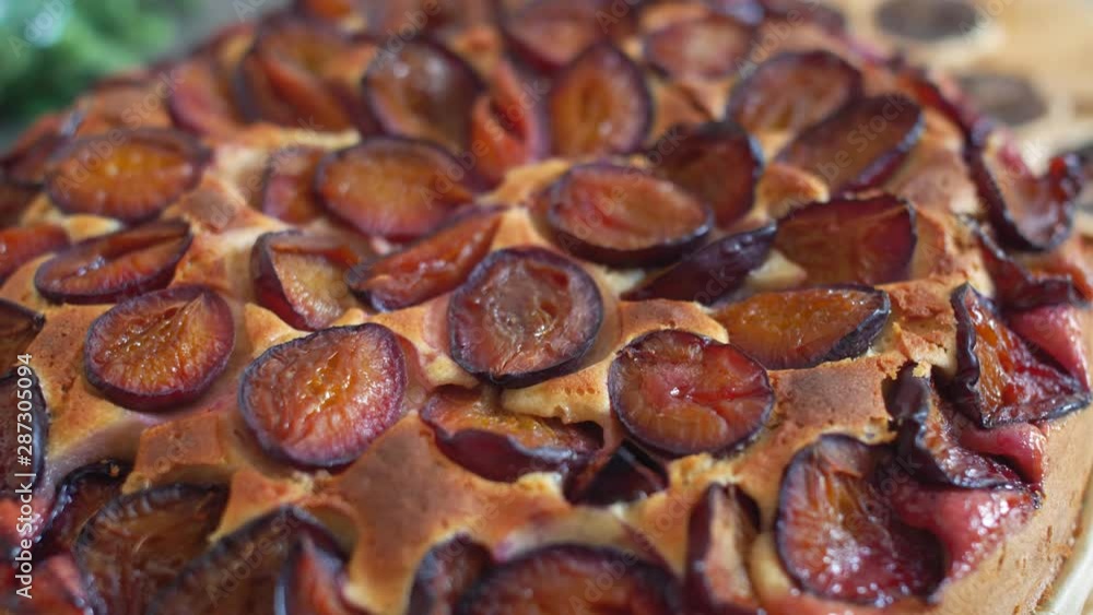 Delicious plum pie with sliced plums on the kitchen wood board. Close up of sweet food. 4k. Delicious plum pie with sliced plums on the kitchen wood board. Close up of sweet food. 4k.