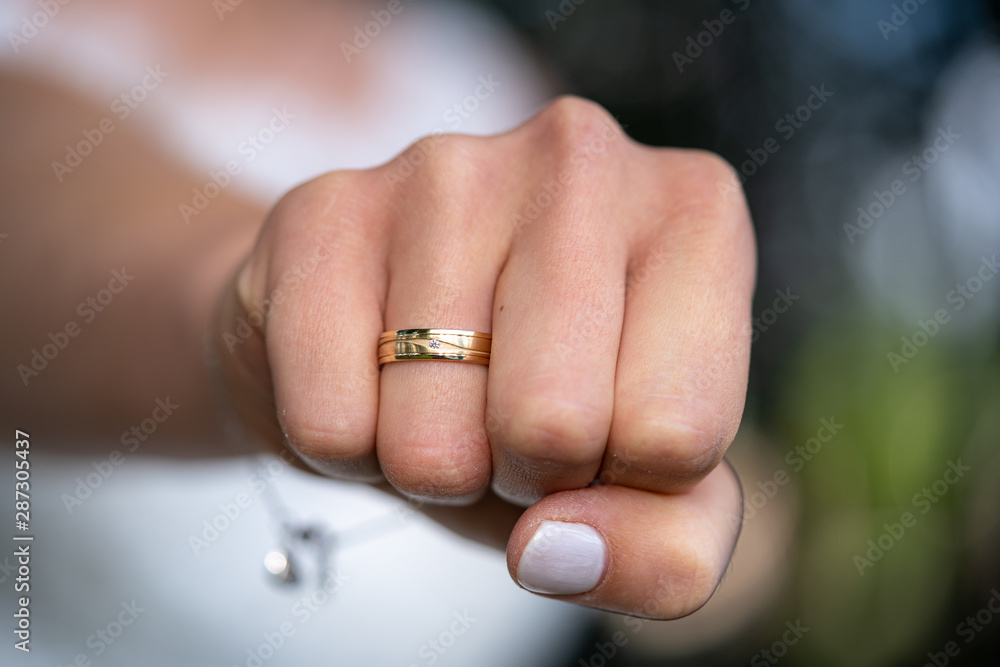 Close up of happy gold ring on woman's finger with diamond