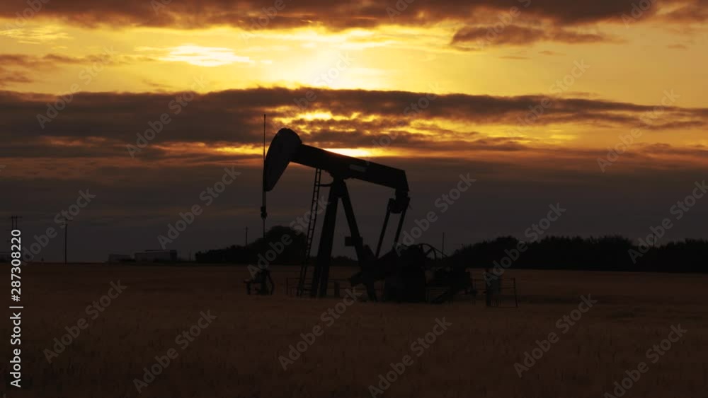 Pump jack. Oil well. Crude oil economy. Oil well, close up. Silhouette of an oil pump jack on rig as the sun sets in the background. Pump jack. Oil well. Crude oil economy. Oil well, close up. Silhouette of an oil pump jack on rig as the sun sets in the background.