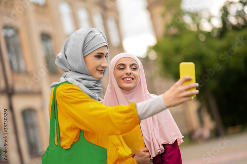 Beautiful young muslim women making selfie near university