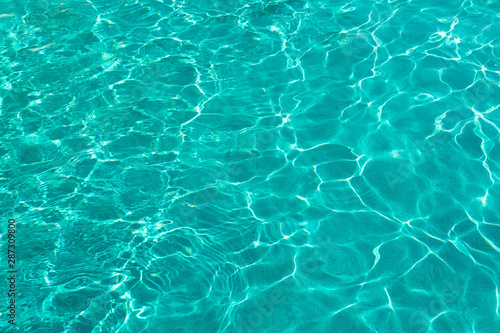 Water ripples on blue tiled swimming pool background. View from above