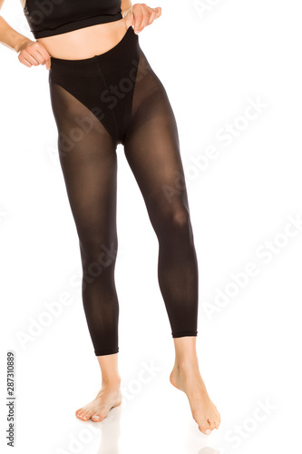 Young woman dressing nylon tights on white background