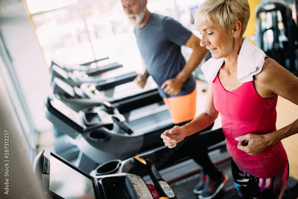 Happy senior people running together on treadmills in gym. Happy senior people running together on treadmills in gym.