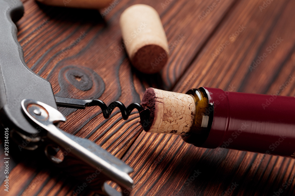 Corkscrew and bottle of wine on the board - Image