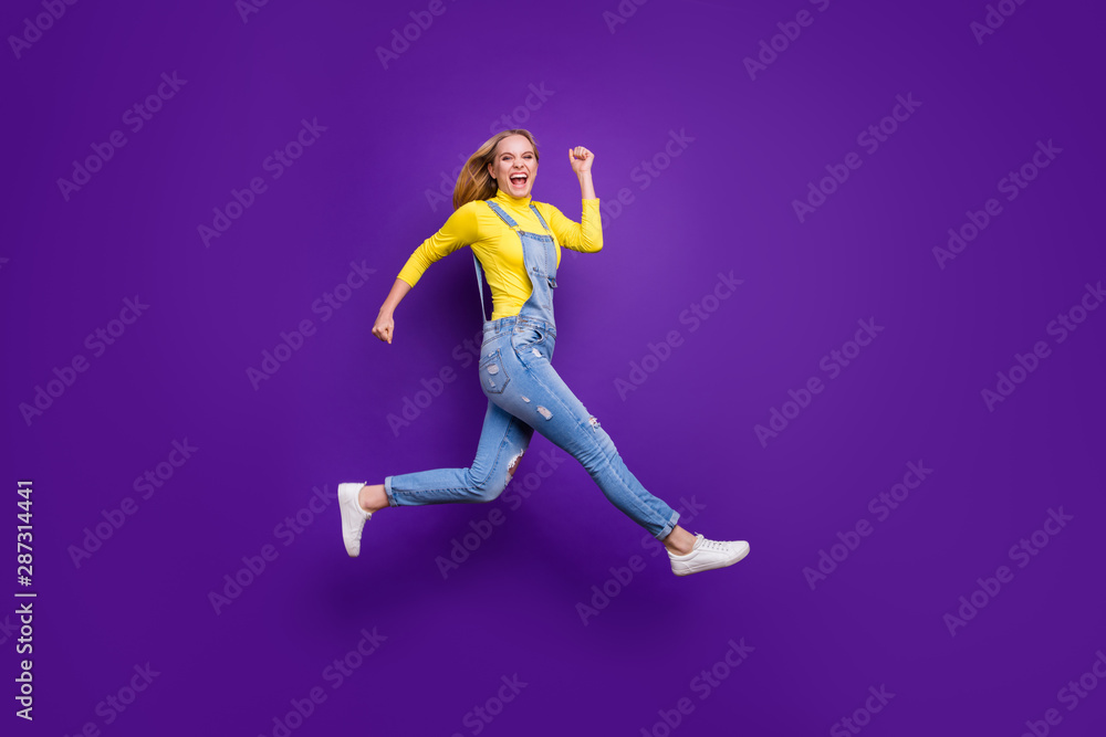 Full length photo of cheerful teenager running screaming wearing yellow turtleneck denim jeans overalls isolated over violet purple background Full length photo of cheerful teenager running screaming wearing yellow turtleneck denim jeans overalls isolated over violet purple background