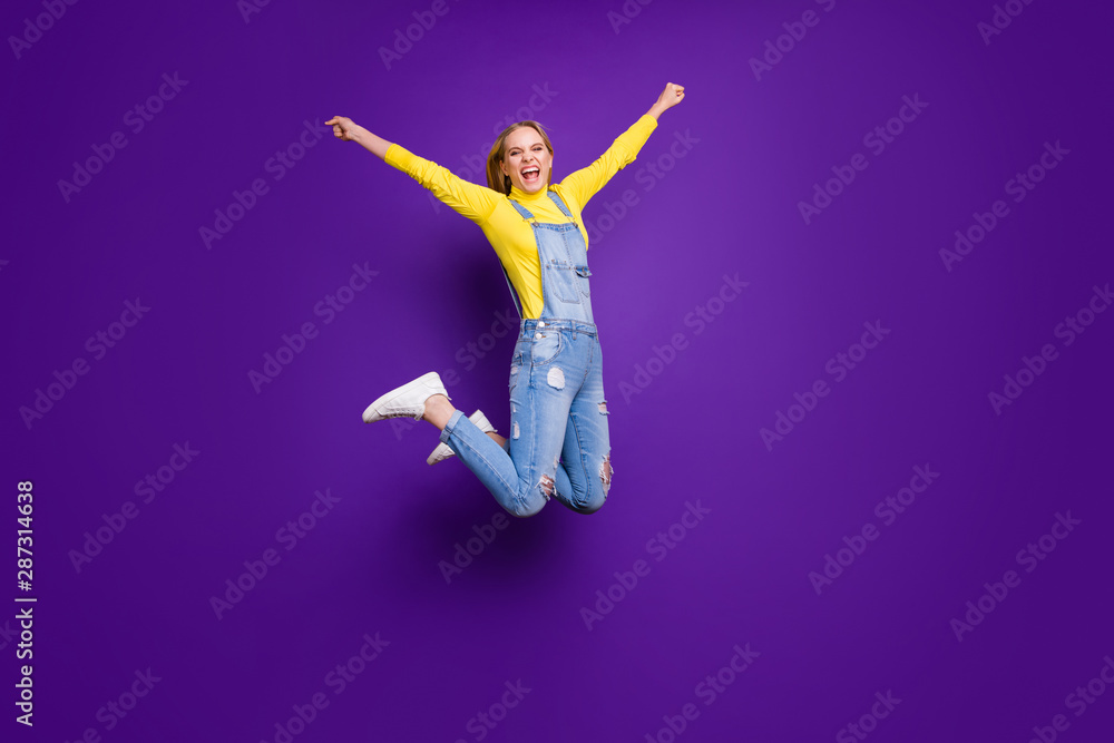 Full length photo of cheerful person screaming yeah raising her hands wearing turtleneck overalls isolated over purple violet background