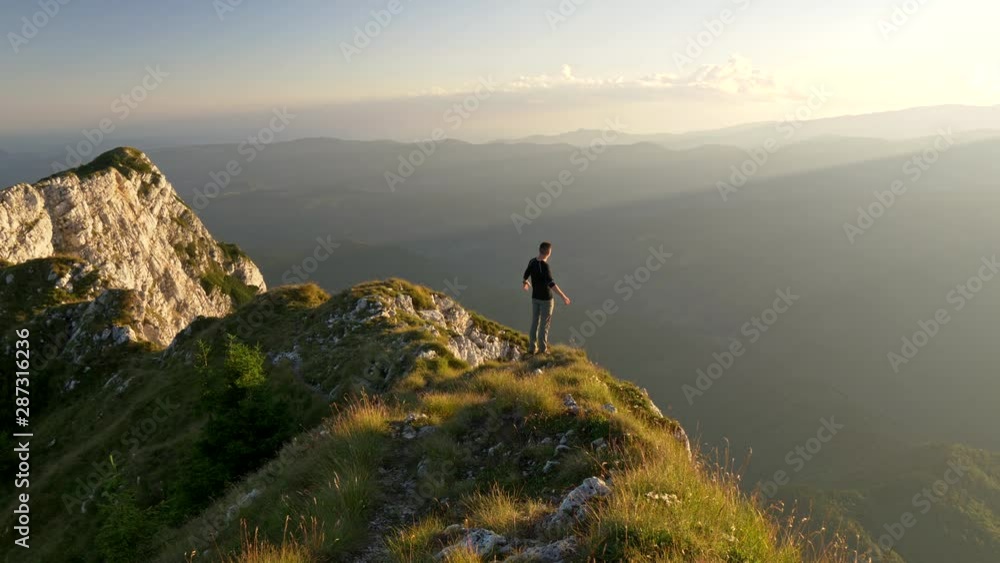 Man standing on top of mountain and raises hands. Sunset view, travel lifestyle concept. UHD, 4K Man standing on top of mountain and raises hands. Sunset view, travel lifestyle concept. UHD, 4K