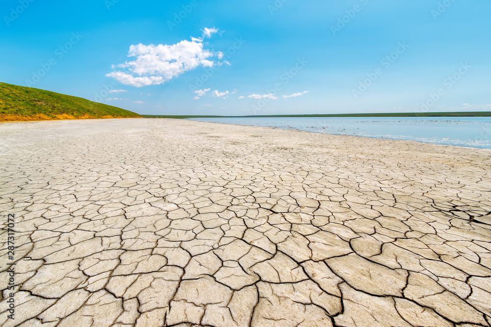 The sunny landscape of the salt lake shore with dry cracked soil. Gruzskoe lake, Rostov-on-Don region, Russia