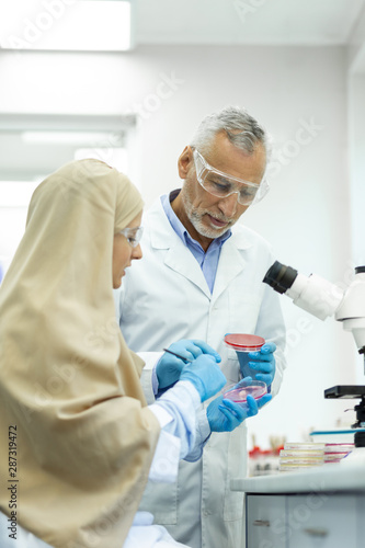 Cheerful mature medical worker consulting his student