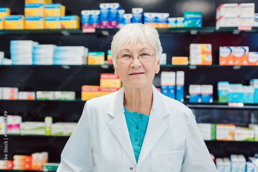 Experienced senior pharmacists in front of shelves in pharmacy Experienced senior pharmacists in front of shelves in pharmacy