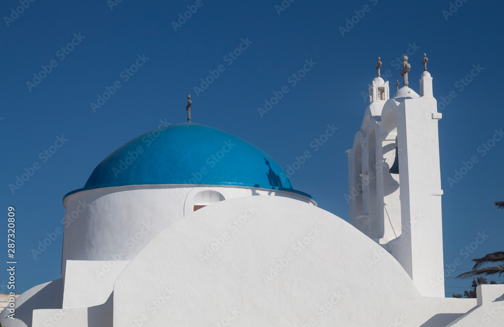 Greece, the island of Sikinos.  The village square. A view of the main church.  Clear blue sky. Brightly painted dome. A simple, traditional building. A summers day, late afternoon.