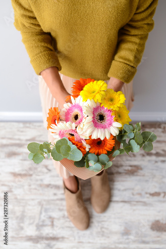 Woman with bouquet of beautiful gerbera flowers indoors