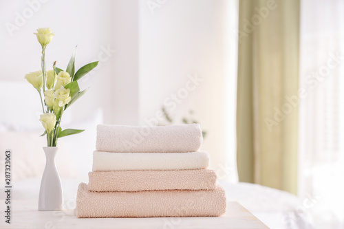 Stack of clean towels on table in bedroom