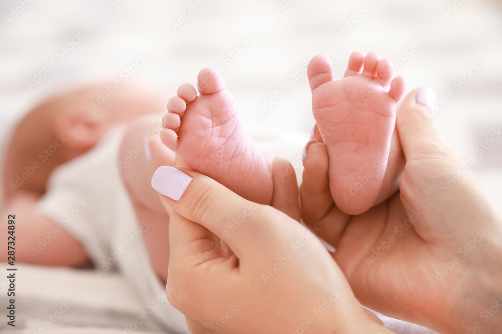 Mother's hands with tiny baby legs, closeup Mother's hands with tiny baby legs, closeup