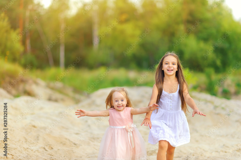 two little girls play outdoors, sisters run holding hands and laughing two little girls play outdoors, sisters run holding hands and laughing