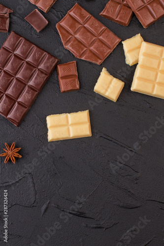 Different chocolate bars on black stone background. Various chocolate bars. Flat lay, copy space.