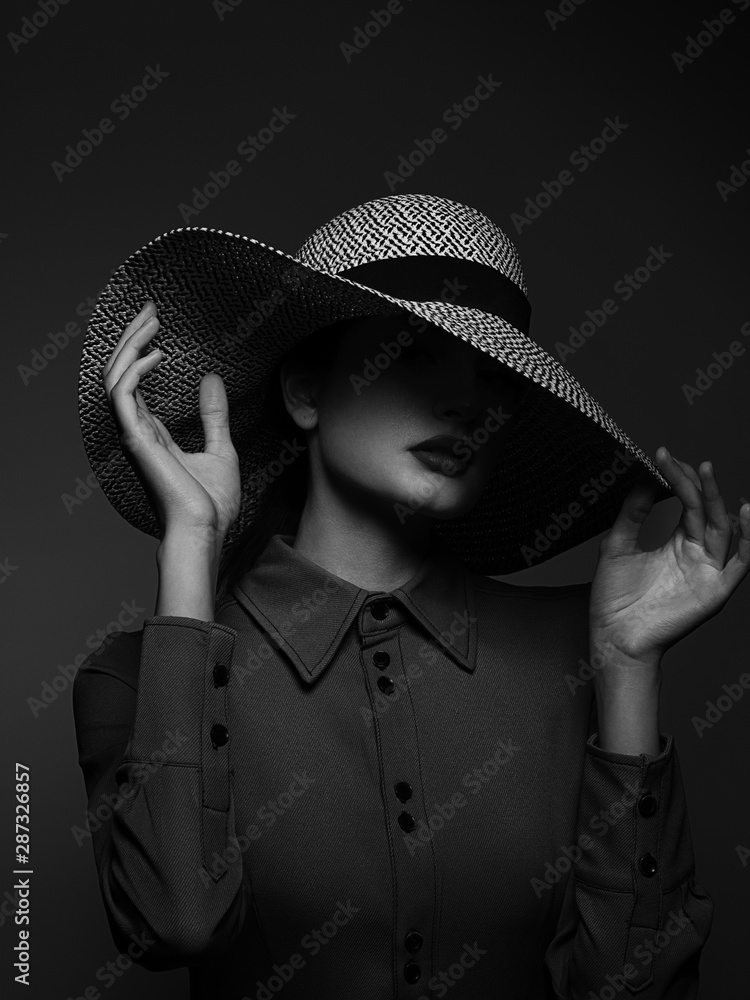 Stockfoto Beautiful woman portrait with red lipstick on lips and a big hat.  Vintage look. Fashion makeup. The hat covers half the face. Black eyeliner  and extremely long eyelashes. Black and white