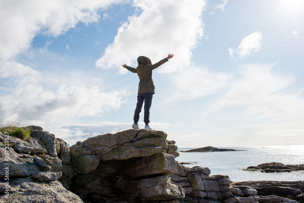 A girl stands high on stones. Success, happiness, freedom. Ocean and clouds. Beautiful nature landscape in Norway. Amazing scenic outdoors view in North. Travel, adventure, lifestyle. Lofoten Islands A girl stands high on stones. Success, happiness, freedom. Ocean and clouds. Beautiful nature landscape in Norway. Amazing scenic outdoors view in North. Travel, adventure, lifestyle. Lofoten Islands