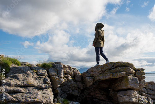 A girl stands high on stones. Success  happiness  freedom. Ocean and clouds. Beautiful nature landscape in Norway. Amazing scenic outdoors view in North. Travel  adventure  lifestyle. Lofoten Islands