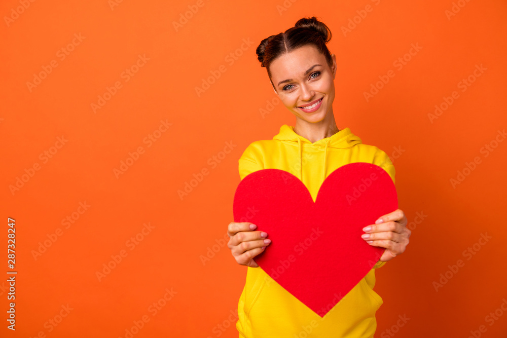 Portrait of charming youth holding hand paper card valentine giving to you wearing stylish sweater isolated over orange background Portrait of charming youth holding hand paper card valentine giving to you wearing stylish sweater isolated over orange background
